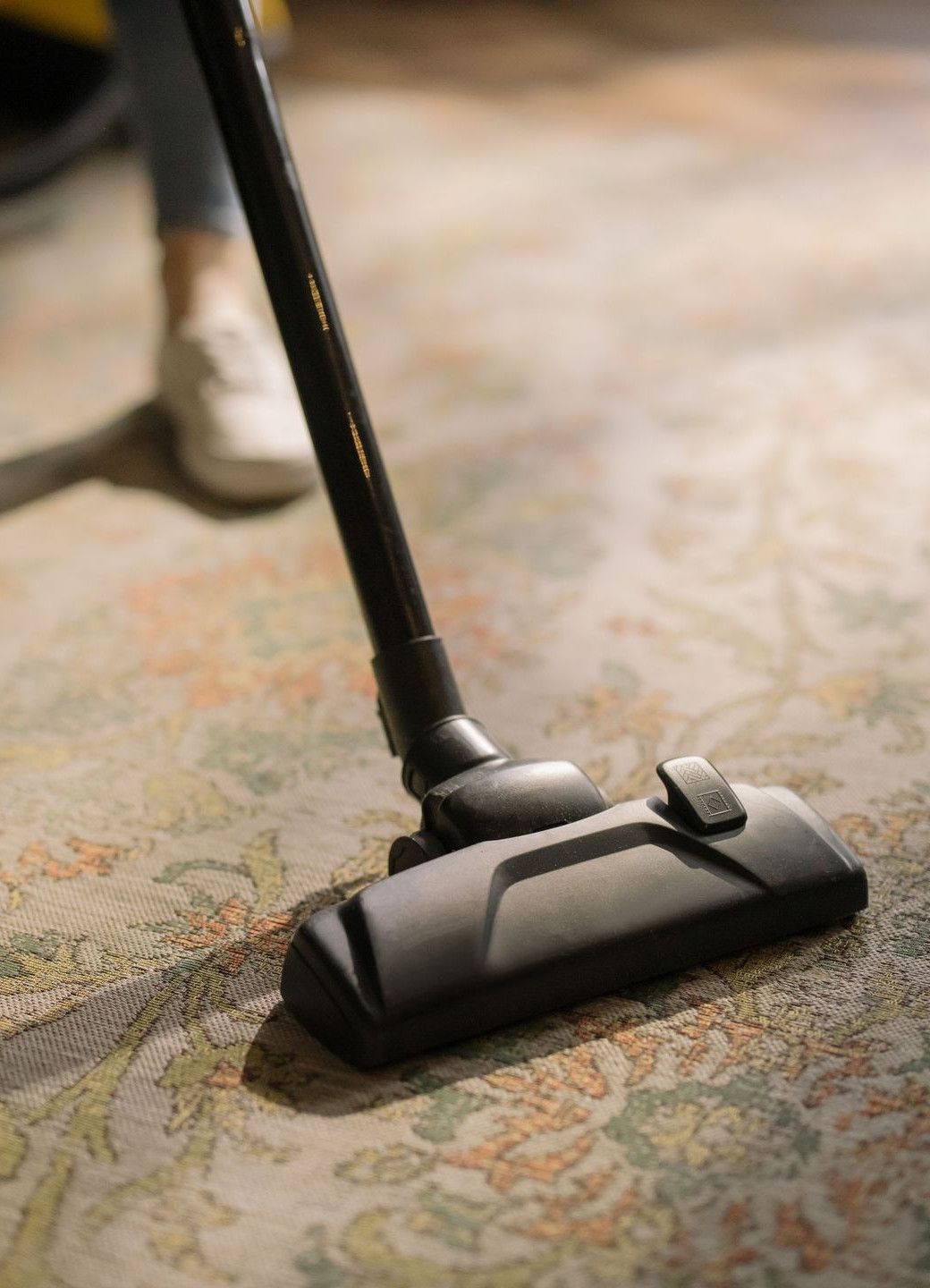 Close-up of a vacuum cleaner on a patterned carpet in a sunlit room, capturing a moment of household cleaning.